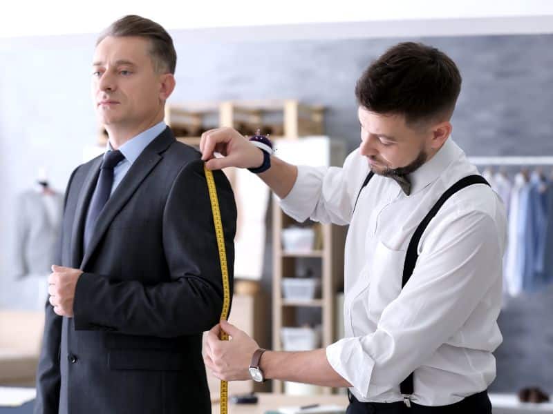 man in getting measured from tailor